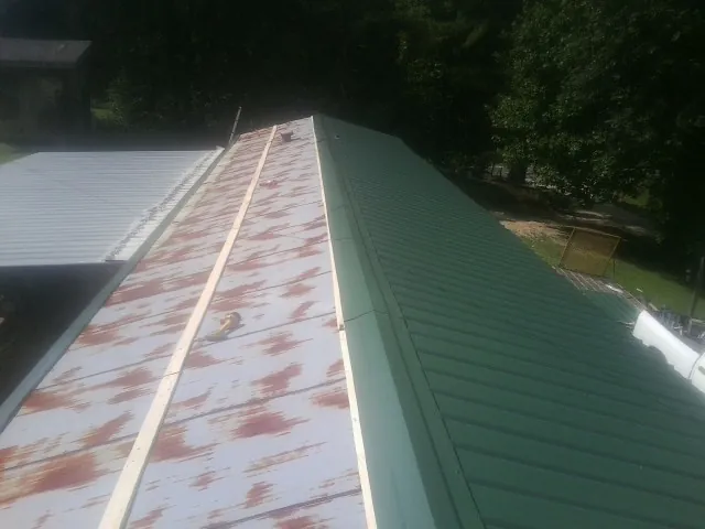 Old rusted panels beside newly installed green metal roofing — Wind Damage Roof Repair by Roofing Brothers in Ivins