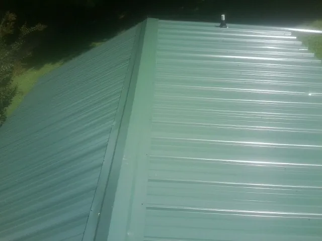 New green metal panels meeting at the ridge of a roof — Flat Roof Repair work by our crew in Ivins
