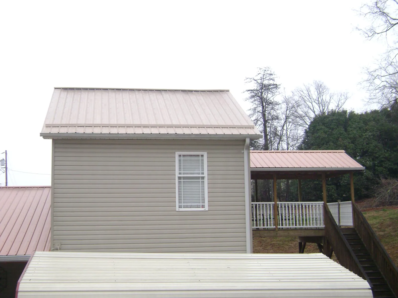 Tan metal roofs on a two story addition and attached porch, from a Roof Replacement job in Ivins