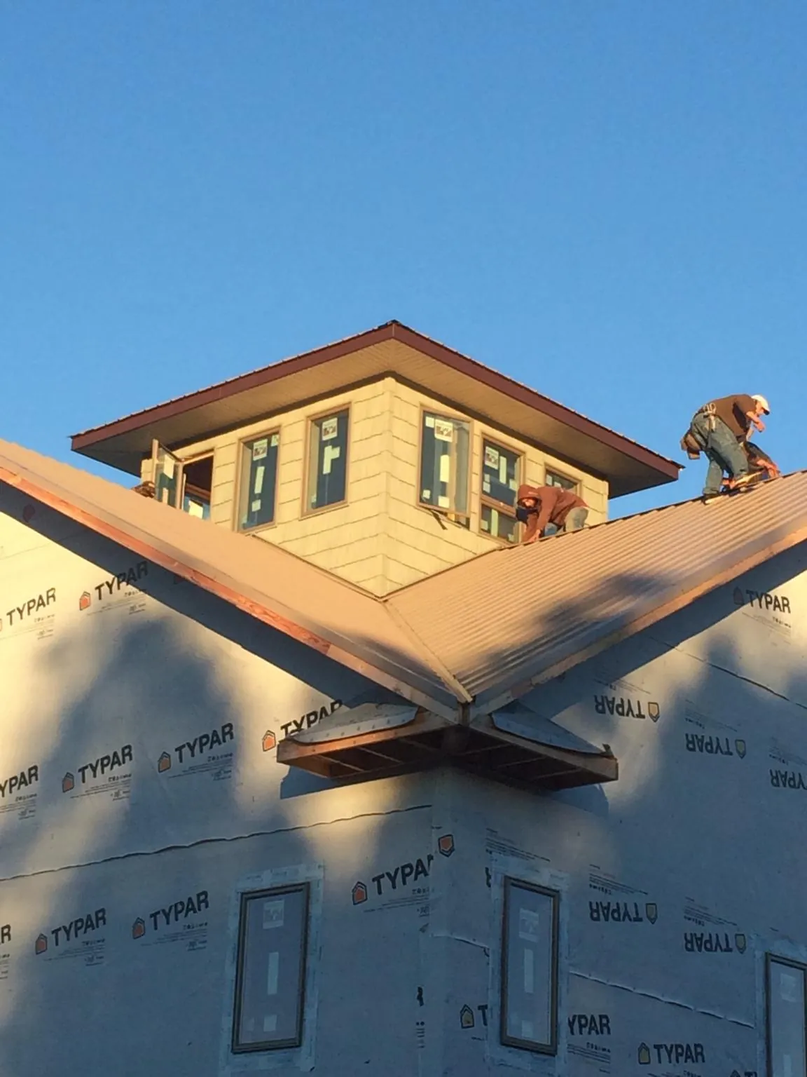 Roofers working around a rooftop cupola on a new metal roof at sunset — Roof Waterproofing in Ivins by Roofing Brothers